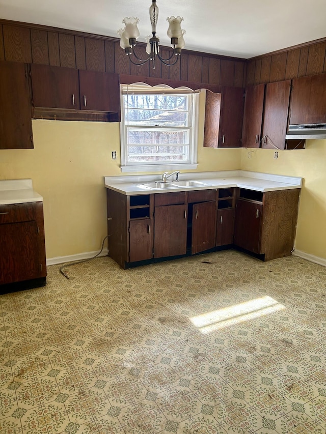 kitchen featuring light countertops, a sink, baseboards, and an inviting chandelier