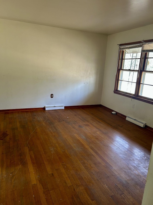 unfurnished room with a baseboard heating unit, baseboards, hardwood / wood-style floors, and baseboard heating