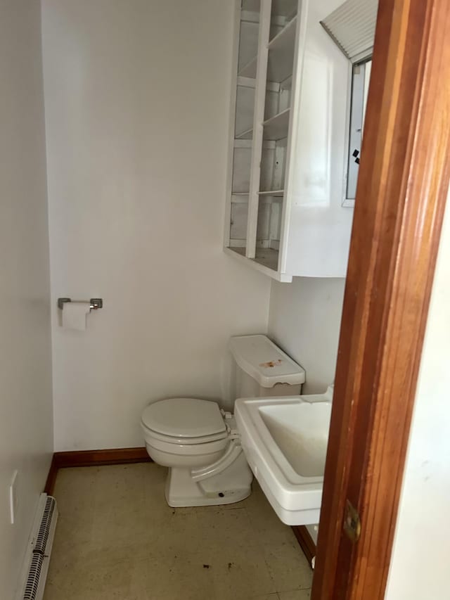 bathroom featuring toilet, a baseboard radiator, baseboards, and a sink