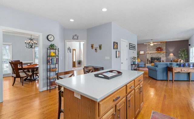 56 Savannah Ct, Daleville, VA 24083 - kitchen with light wood-type flooring, light countertops, a kitchen bar, a brick fireplace, and a kitchen island