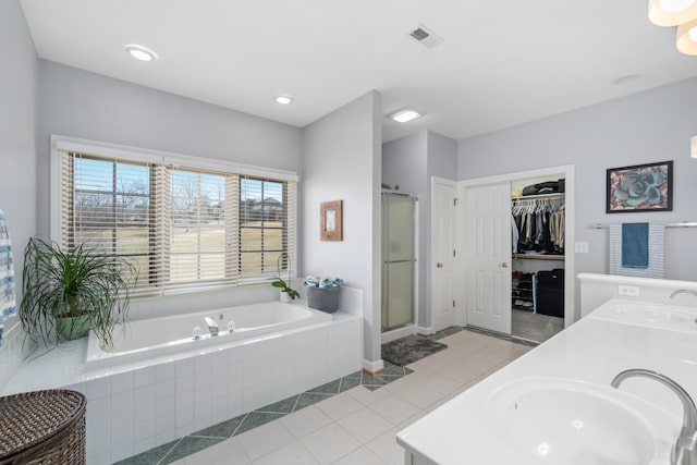 bathroom featuring a bath, tile patterned flooring, double vanity, and a sink