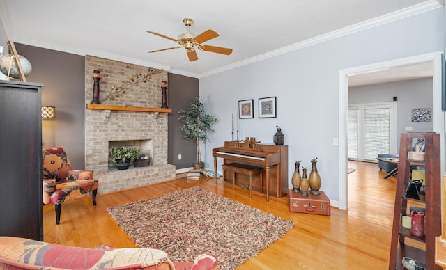 living room with ornamental molding, a fireplace, baseboards, and wood finished floors