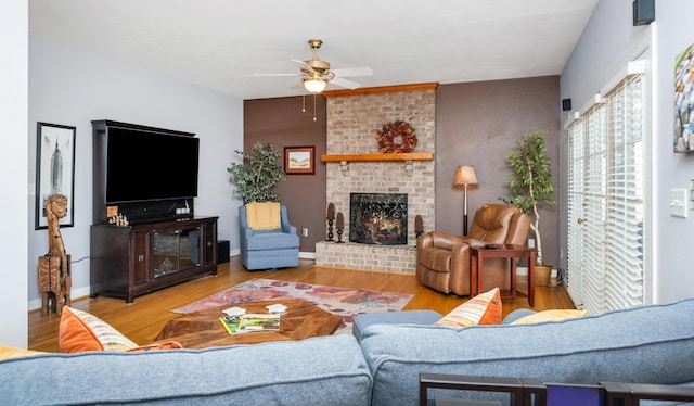 living area featuring a fireplace, wood finished floors, and a ceiling fan