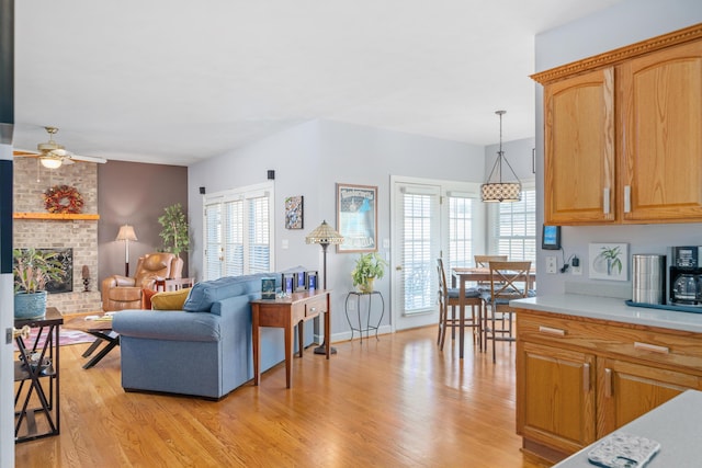 living area featuring ceiling fan, a fireplace, and light wood-style floors