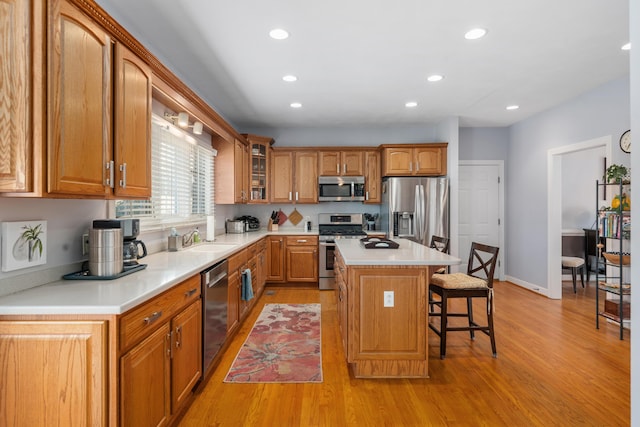 kitchen featuring brown cabinetry, a breakfast bar, a center island, stainless steel appliances, and a sink