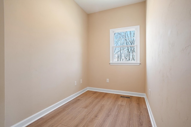 empty room with visible vents, light wood-style flooring, and baseboards