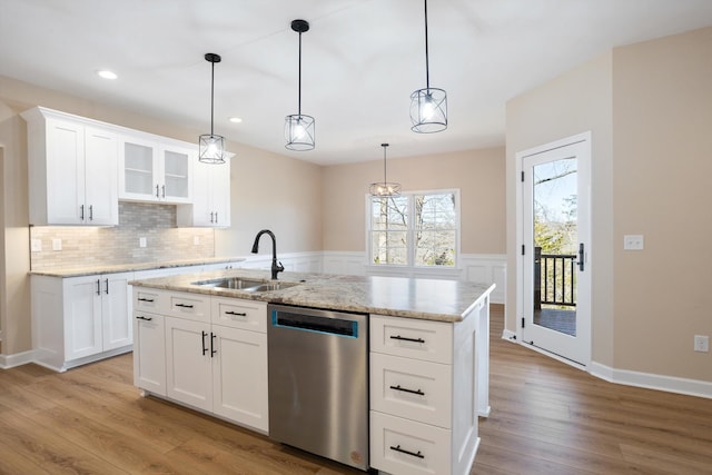 kitchen with a sink, backsplash, light stone countertops, dishwasher, and light wood finished floors