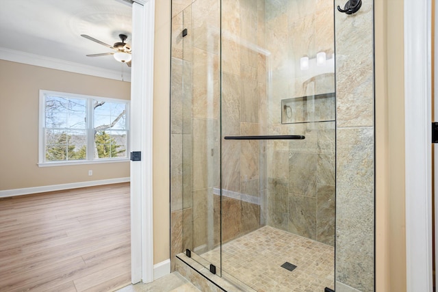 bathroom featuring ornamental molding, a stall shower, a ceiling fan, wood finished floors, and baseboards