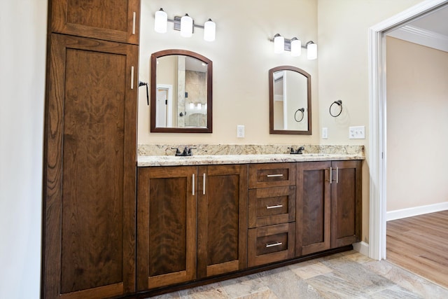 bathroom with double vanity, baseboards, and a sink