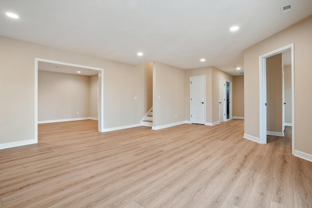 spare room with baseboards, visible vents, light wood-style flooring, stairs, and recessed lighting