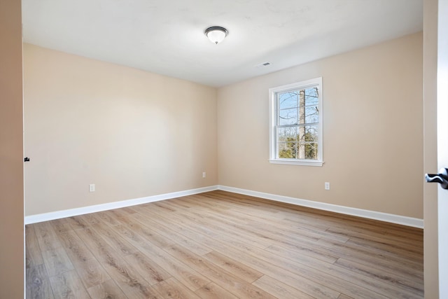 unfurnished room featuring visible vents, baseboards, and wood finished floors