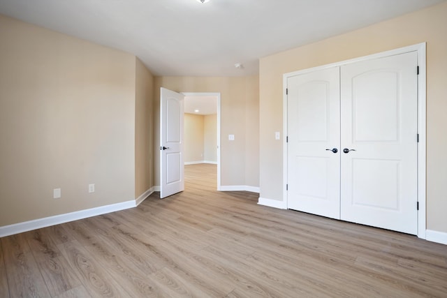 unfurnished bedroom with light wood-type flooring, a closet, and baseboards