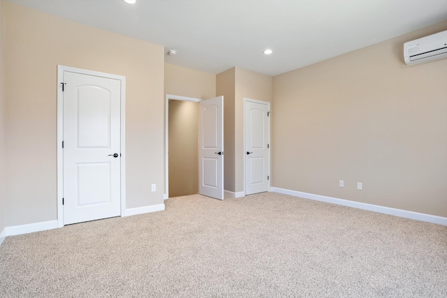 unfurnished bedroom featuring recessed lighting, a wall mounted air conditioner, baseboards, and light colored carpet