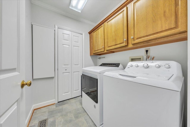 clothes washing area featuring washing machine and dryer, visible vents, ornamental molding, cabinet space, and stone finish floor