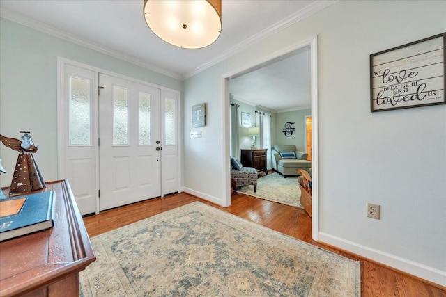 entrance foyer featuring baseboards, wood finished floors, and crown molding