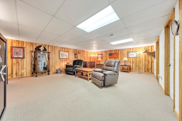 living room featuring carpet, a drop ceiling, and wood walls