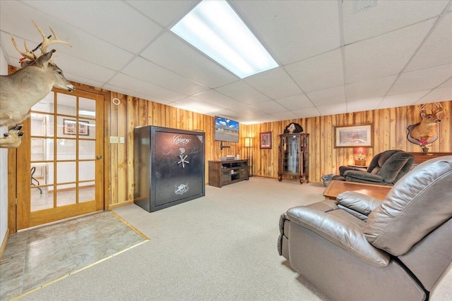 unfurnished living room with wooden walls, a drop ceiling, and light colored carpet