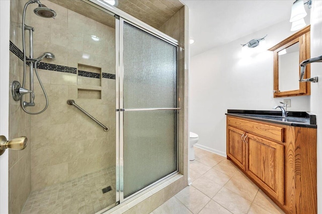 bathroom featuring toilet, a stall shower, vanity, and tile patterned floors