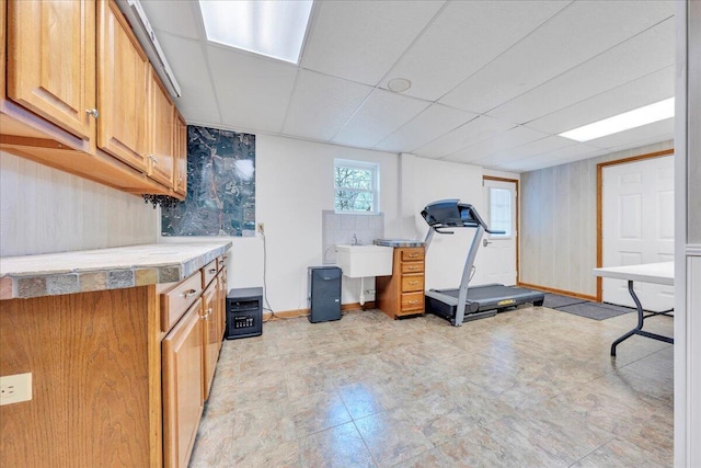 interior space featuring a paneled ceiling, baseboards, and a sink