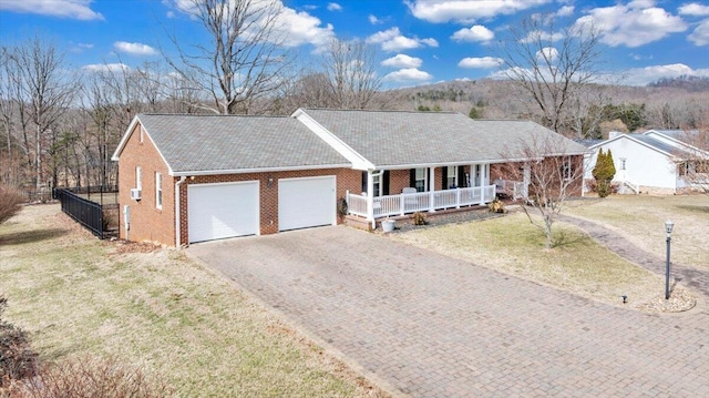 single story home with brick siding, a porch, a front yard, a garage, and driveway