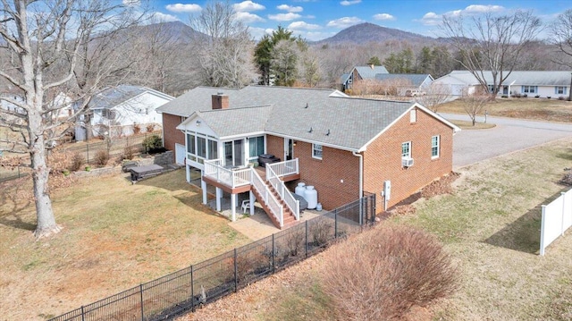 rear view of property with a sunroom, stairway, a deck with mountain view, a yard, and brick siding