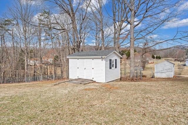 garage featuring fence and a shed