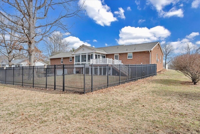 back of house with a sunroom, a yard, fence, and brick siding