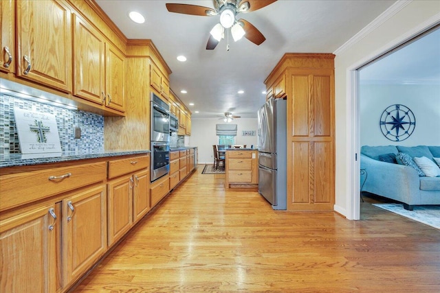 kitchen with light wood finished floors, tasteful backsplash, dark stone counters, ornamental molding, and freestanding refrigerator