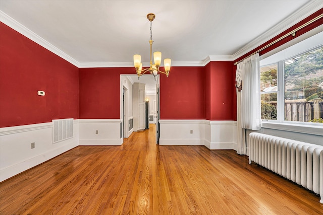 unfurnished room featuring a wainscoted wall, radiator heating unit, visible vents, and an inviting chandelier