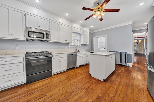 kitchen featuring stainless steel appliances, a kitchen island, radiator heating unit, dark wood finished floors, and crown molding