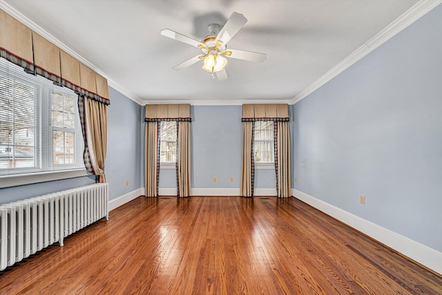 empty room with radiator heating unit, baseboards, crown molding, and wood finished floors