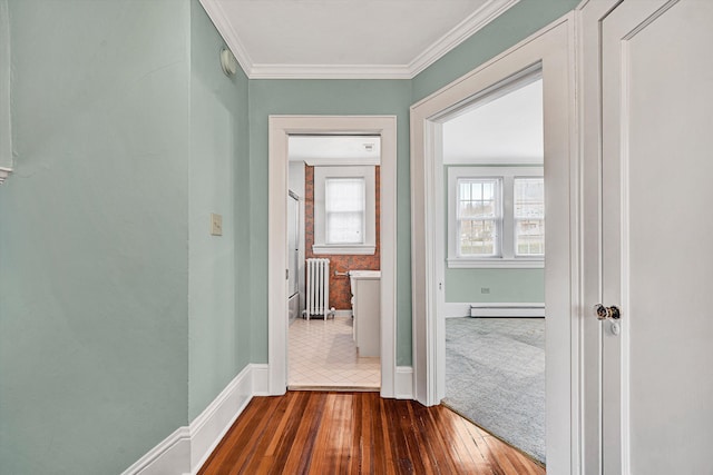 hallway featuring baseboards, radiator heating unit, wood finished floors, baseboard heating, and crown molding