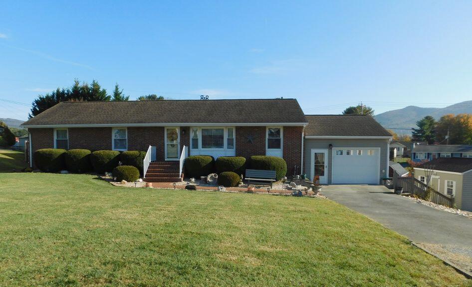 ranch-style house featuring a garage, a front yard, brick siding, and driveway