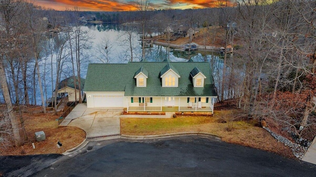 cape cod house with a garage, a water view, covered porch, and driveway