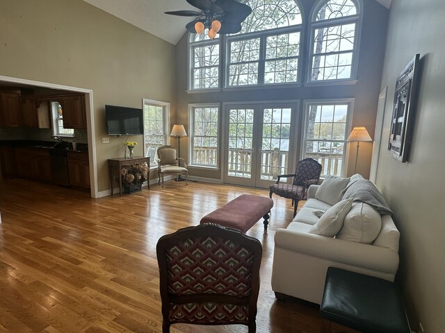 living area featuring french doors, lofted ceiling, ceiling fan, and wood finished floors