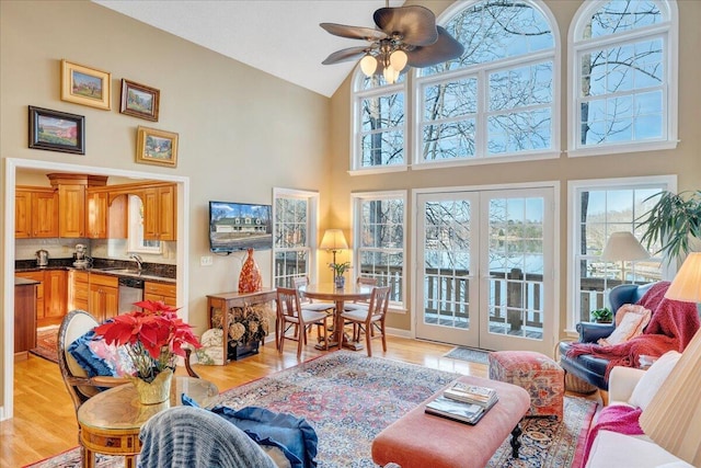 living area featuring high vaulted ceiling, french doors, a ceiling fan, and light wood-style floors