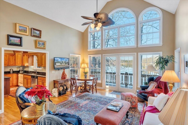 living area with french doors, plenty of natural light, light wood-style floors, and a ceiling fan