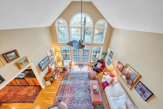 living area featuring a textured ceiling, high vaulted ceiling, ceiling fan, and wood finished floors