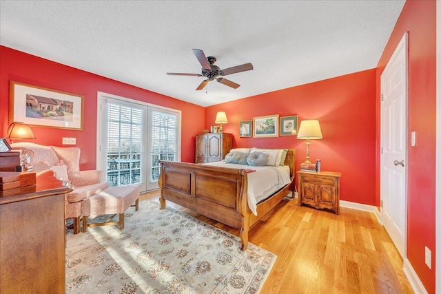 bedroom featuring light wood-type flooring, a ceiling fan, a textured ceiling, baseboards, and access to exterior