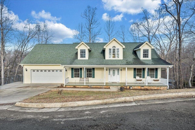 new england style home featuring a porch, concrete driveway, an attached garage, and a shingled roof