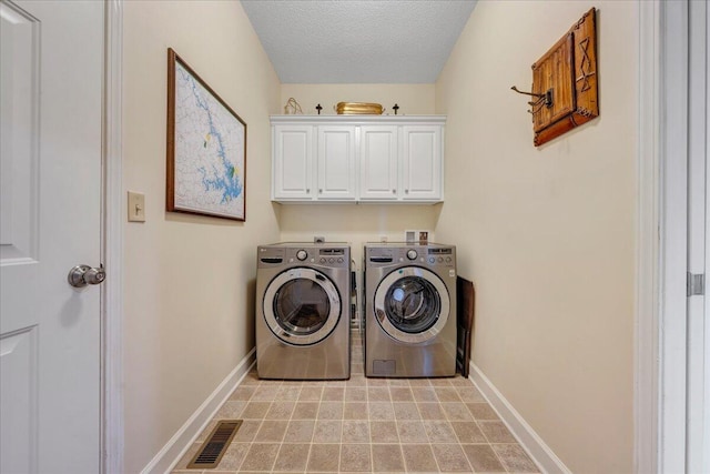 washroom featuring baseboards, cabinet space, visible vents, and washing machine and clothes dryer