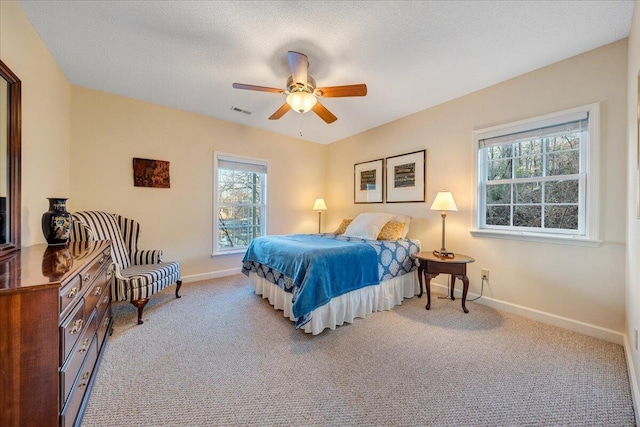 carpeted bedroom featuring visible vents, baseboards, a textured ceiling, and a ceiling fan