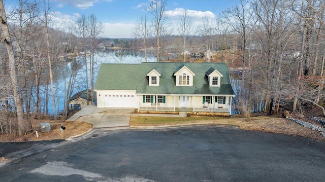 cape cod house with a garage, a water view, covered porch, and concrete driveway