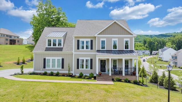 view of front of house with a porch, a standing seam roof, a front lawn, and board and batten siding