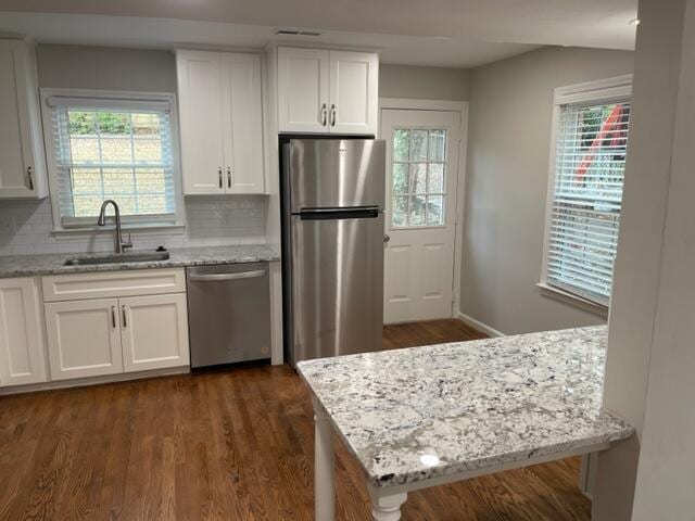 kitchen featuring decorative backsplash, dark wood-type flooring, stainless steel appliances, white cabinetry, and a sink