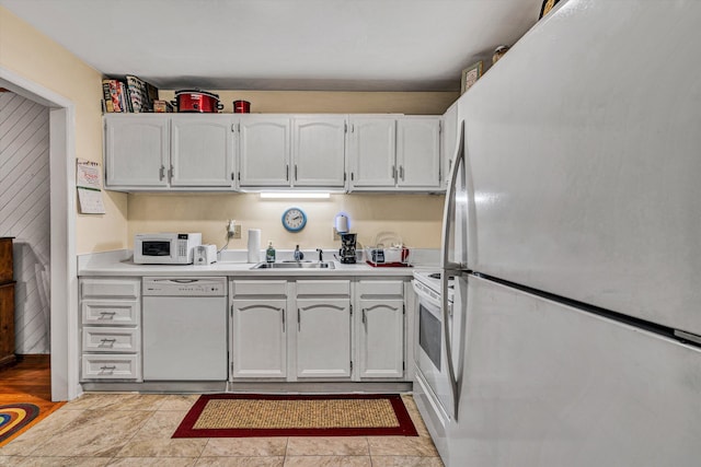 kitchen with white appliances, light countertops, a sink, and white cabinets