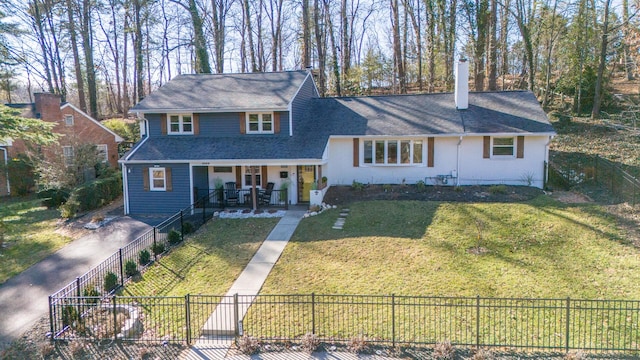 view of front facade featuring fence private yard, covered porch, driveway, and a front lawn