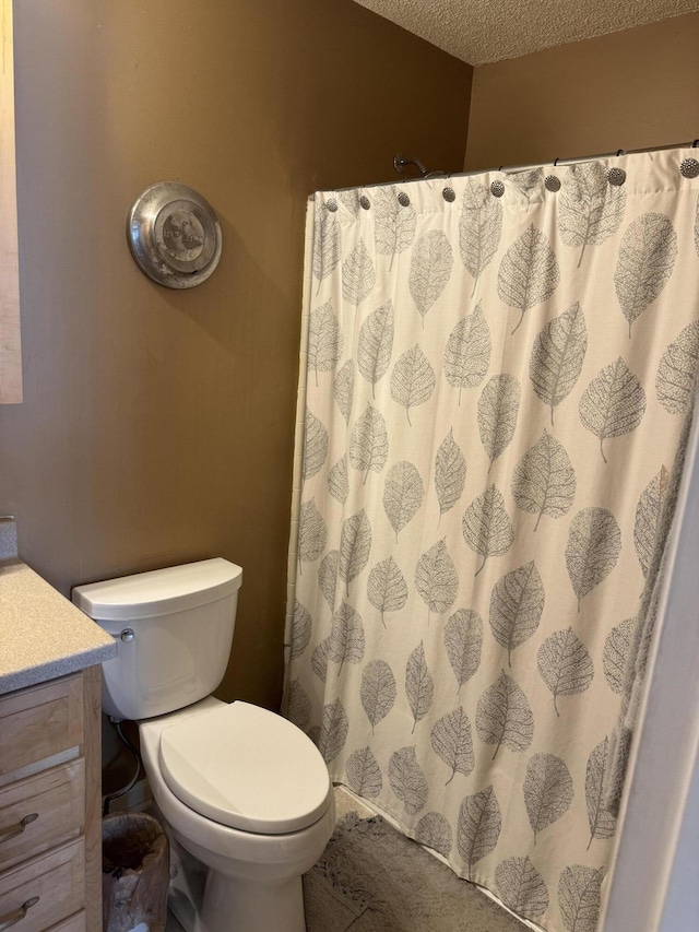 bathroom with toilet, curtained shower, a textured ceiling, and vanity