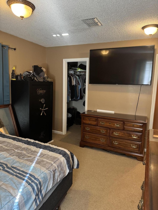 carpeted bedroom featuring a textured ceiling, a spacious closet, a closet, and visible vents