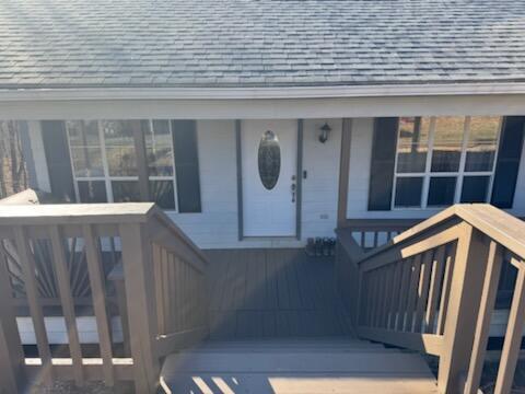 view of exterior entry with roof with shingles